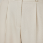 Closeup of cream wide-leg trouser fabric and pleat detail