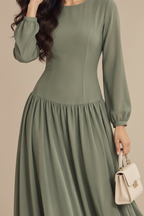 Close-up of the neckline, bodice seams and drop-waist gathering on the sage maxi dress
